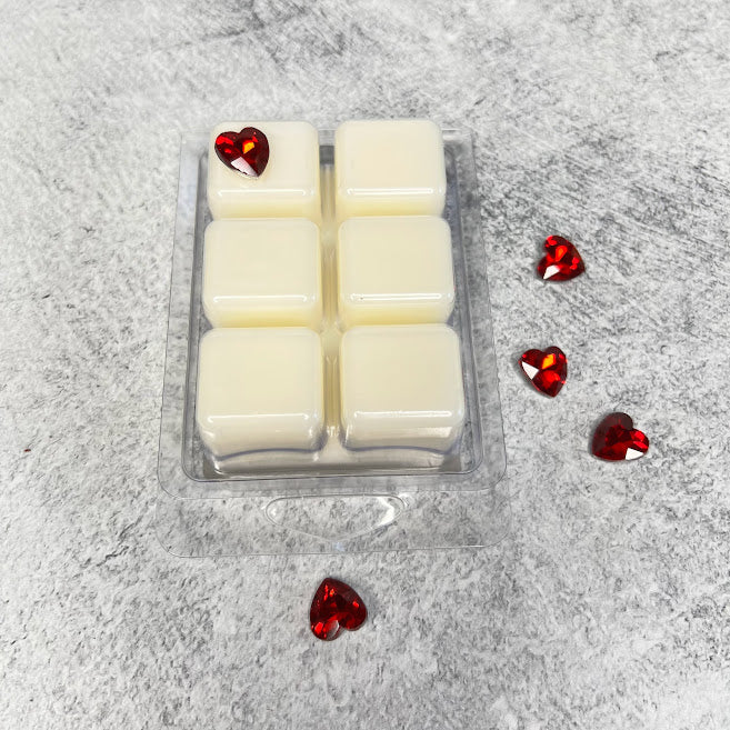 Bottom of wax melts displayed beside red glass hearts. 