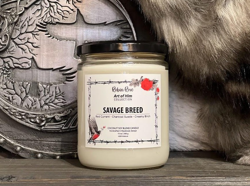 16 oz candle container with natural wax inside. Container label has a robin and a rose on it. Background has a viking shield and rabbit fur