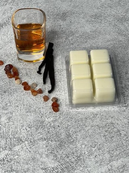 Wax melts are upside down displaying natural wax cubes. A shot of bourbon and vanilla next to it